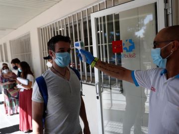 Un sanitario toma la temperatura a una de las personas que esperan su turno para realizarse una prueba de PCR dentro del Plan COVID-19 de la Comunidad de Madrid.