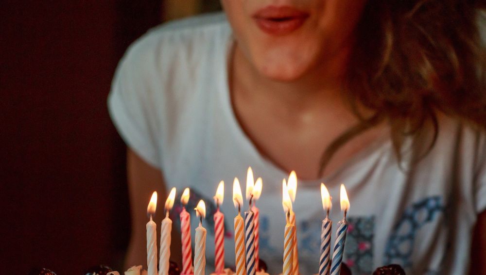 Imagen de archivo de una joven soplando las velas de una tarta