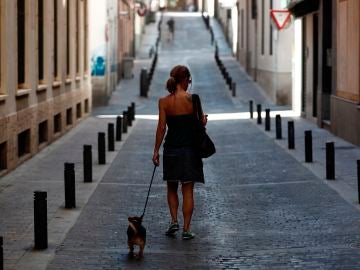 Una mujer pasea con su perro por una calle desierta del centro de Madrid