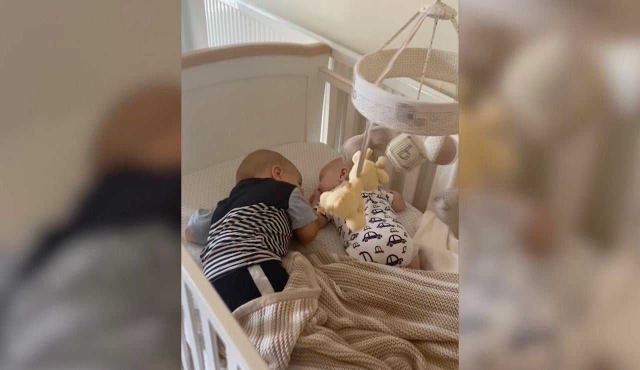el bebé arropa a su hermano en la cuna
