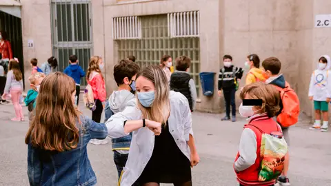 Una profesora realiza un saludo con el codo junto a una alumna Una profesora realiza un saludo con el codo junto a una alumna