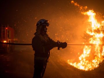  Varios bomberos realizan labores de extinción hoy domingo en el incendio forestal de Cualedro, Ourense