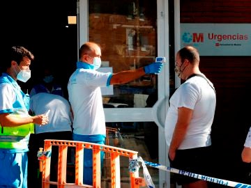 Un paramédico toma la temperatura a un ciudadano antes de acceder al centro de salud Reyes Católicos