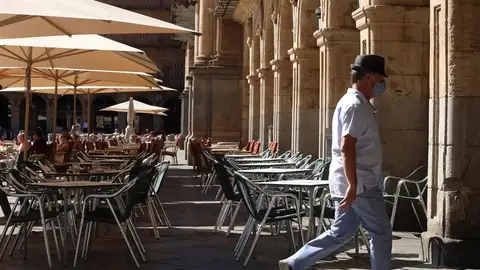 Un hombre con mascarilla pasa frente a una terraza de un restaurante de la plaza mayor de Salamanca. Un hombre con mascarilla pasa frente a una terraza de un restaurante de la plaza mayor de Salamanca.