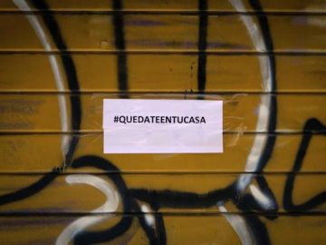Imagen de un comercio cerrado con un cartel de Quedateentucasa