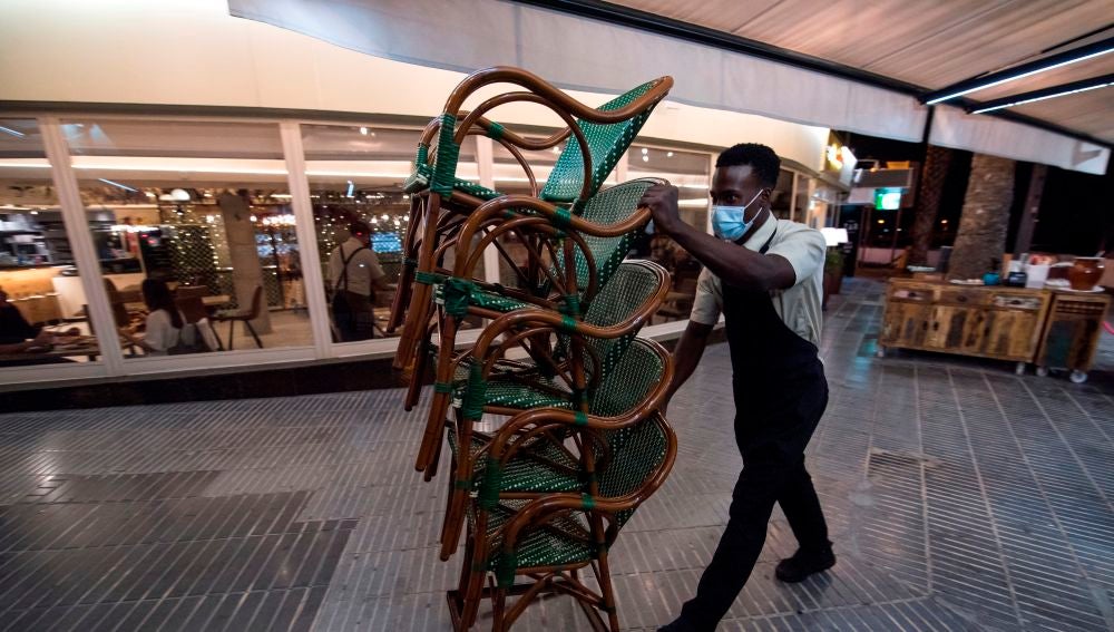 Un hostelero recoge el mobiliario de su terraza en Mallorca