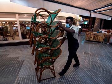 Un hostelero recoge el mobiliario de su terraza en Mallorca