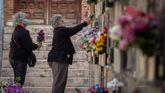 Varias mujeres colocan flores en una tumba del cementerio de Alcal&aacute;