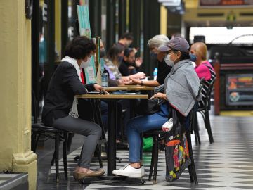 Ciudadanos con mascarilla tomando algo en una cafetería