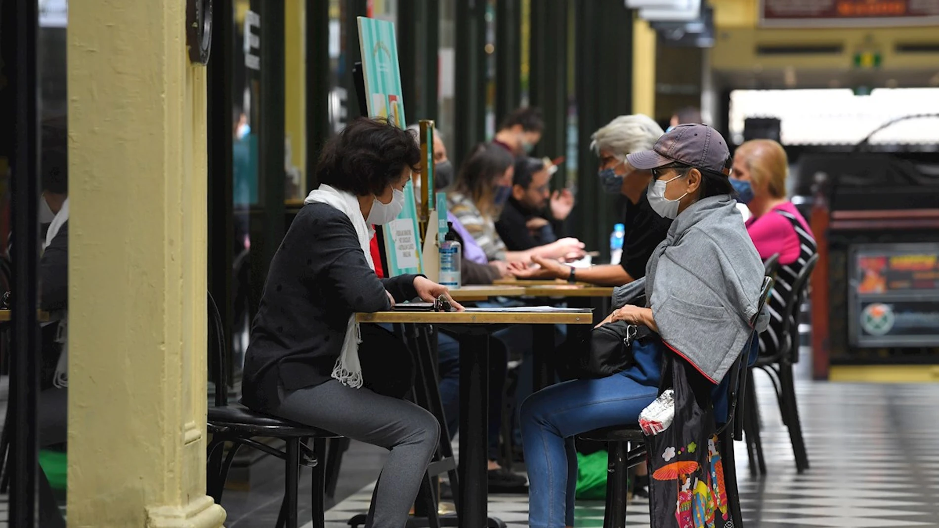 Ciudadanos con mascarilla tomando algo en una cafetería Ciudadanos con mascarilla tomando algo en una cafetería