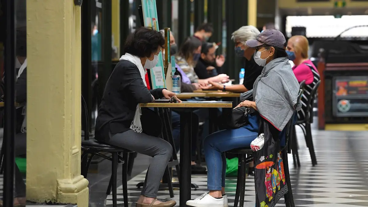 Ciudadanos con mascarilla tomando algo en una cafetería Ciudadanos con mascarilla tomando algo en una cafetería