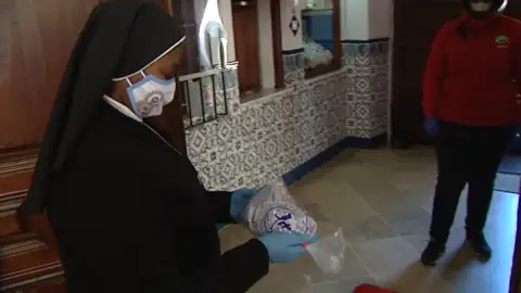 Una monja entrega un dulce navideño a un repartidor de Telepizza Una monja entrega un dulce navideño a un repartidor de Telepizza