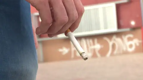 Una persona con un cigarrillo en la mano Una persona con un cigarrillo en la mano