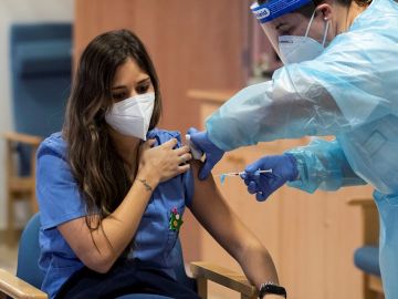 Imagen de una sanitaria mientras le inyectan la vacuna