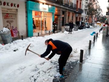 Un vecino retira nieve de la calzada en calle León de Madrid. 