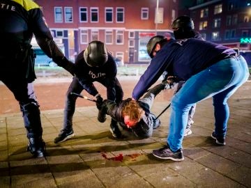 Un hombre es reducido por varios policías durante los distubios registrados anoche en Rotterdam, Países Bajos