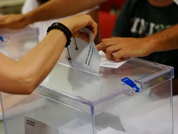 Una persona deposita su voto en una urna Una persona deposita su voto en una urna