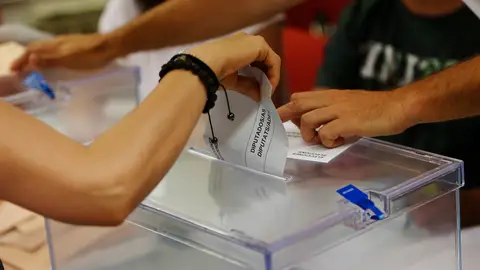 Una persona deposita su voto en una urna Una persona deposita su voto en una urna