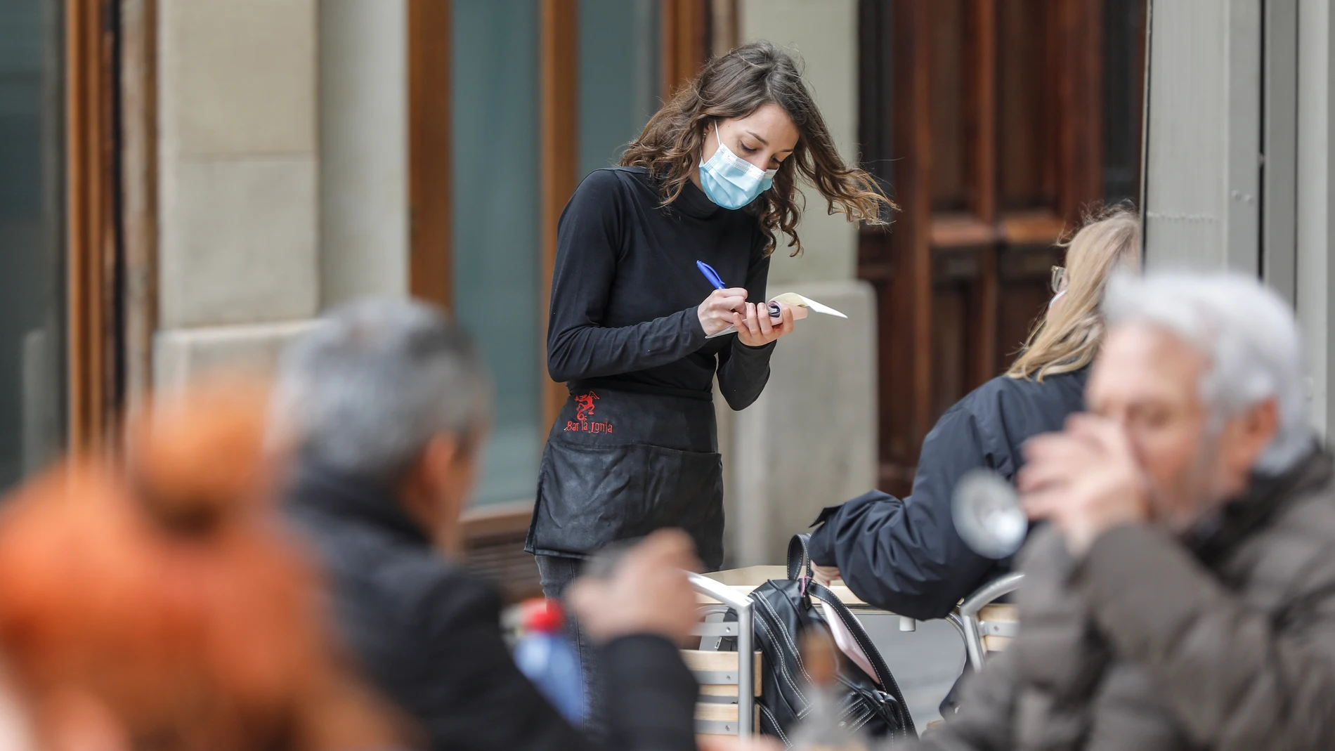 Una camarera atiende a varios clientes Una camarera atiende a varios clientes