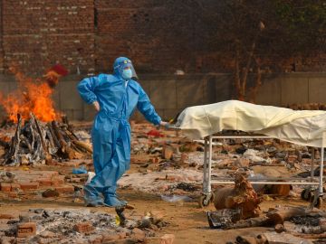 Un sanitario quema los cadáveres de muertos por COVID-19 en India