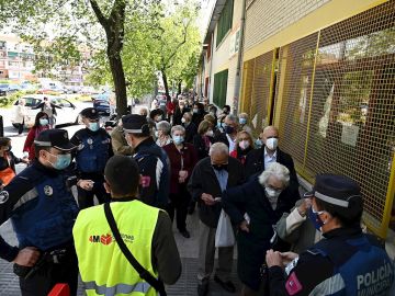 Votantes de las elecciones de Madrid esperan su turno para ejercer su derecho al voto en el Colegio Pinar del Rey en Madrid, este martes