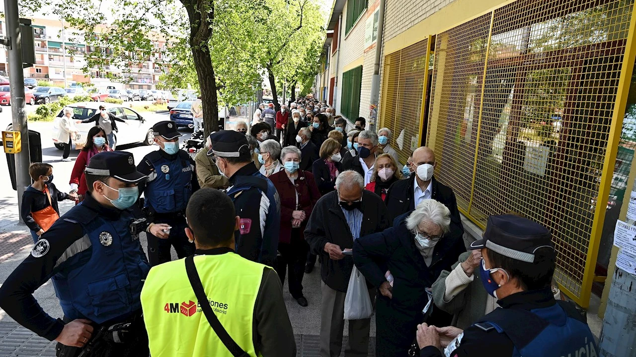 Votantes de las elecciones de Madrid esperan su turno para ejercer su derecho al voto en el Colegio Pinar del Rey en Madrid, este martes
