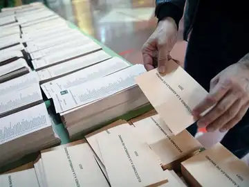 Un miembro de una mesa electoral coloca las papeletas Un miembro de una mesa electoral coloca las papeletas