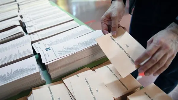 Un miembro de una mesa electoral coloca las papeletas Un miembro de una mesa electoral coloca las papeletas