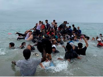 Un grupo de personas se hacen con una embarcación de las autoridades marroquíes en la playa de la localidad de Fnideq (Castillejos) 