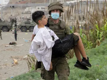 Un soldado del Ejército de Tierra ayuda a un inmigrante que ha logrado cruzar uno de los espigones fronterizos de Ceuta este martes en una avalancha de inmigrantes sin precedentes en España al registrarse la entrada en 24 horas de 5.000 personas (un tercio de ellas menores). Un soldado del Ejército de Tierra ayuda a un inmigrante que ha logrado cruzar uno de los espigones fronterizos de Ceuta este martes en una avalancha de inmigrantes sin precedentes en España al registrarse la entrada en 24 horas de 5.000 personas (un tercio de ellas menores).