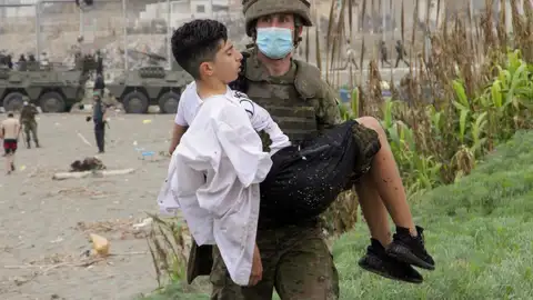 Un soldado del Ejército de Tierra ayuda a un inmigrante que ha logrado cruzar uno de los espigones fronterizos de Ceuta este martes en una avalancha de inmigrantes sin precedentes en España al registrarse la entrada en 24 horas de 5.000 personas (un tercio de ellas menores). Un soldado del Ejército de Tierra ayuda a un inmigrante que ha logrado cruzar uno de los espigones fronterizos de Ceuta este martes en una avalancha de inmigrantes sin precedentes en España al registrarse la entrada en 24 horas de 5.000 personas (un tercio de ellas menores).