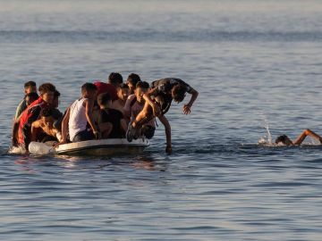 Varios menores migrantes se lanzan al agua para alcanzar la playa ceutí de El Tarajal mientras intentan llegar a España a bordo de una barca este miércoles.