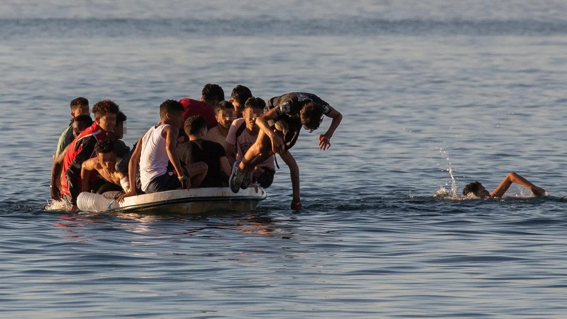 Varios menores migrantes se lanzan al agua para alcanzar la playa ceutí de El Tarajal mientras intentan llegar a España a bordo de una barca este miércoles.