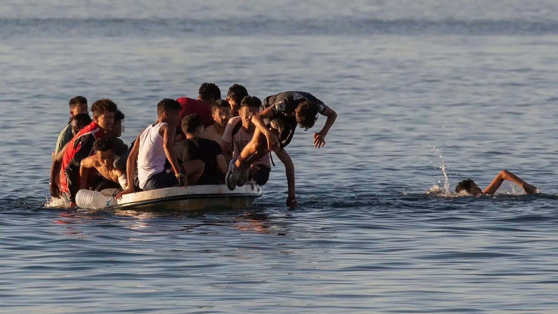 Varios menores migrantes se lanzan al agua para alcanzar la playa ceut&iacute; de El Tarajal mientras intentan llegar a Espa&ntilde;a a bordo de una barca este mi&eacute;rcoles.