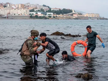 Un miembro del Ejército ayuda a menores migrantes llegados a Ceuta. Un miembro del Ejército ayuda a menores migrantes llegados a Ceuta.