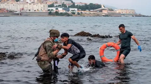 Un miembro del Ejército ayuda a menores migrantes llegados a Ceuta. Un miembro del Ejército ayuda a menores migrantes llegados a Ceuta.