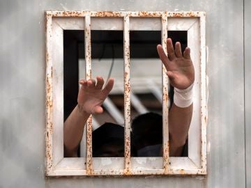 Dos menores sacan sus manos por una ventana del albergue de Piniers