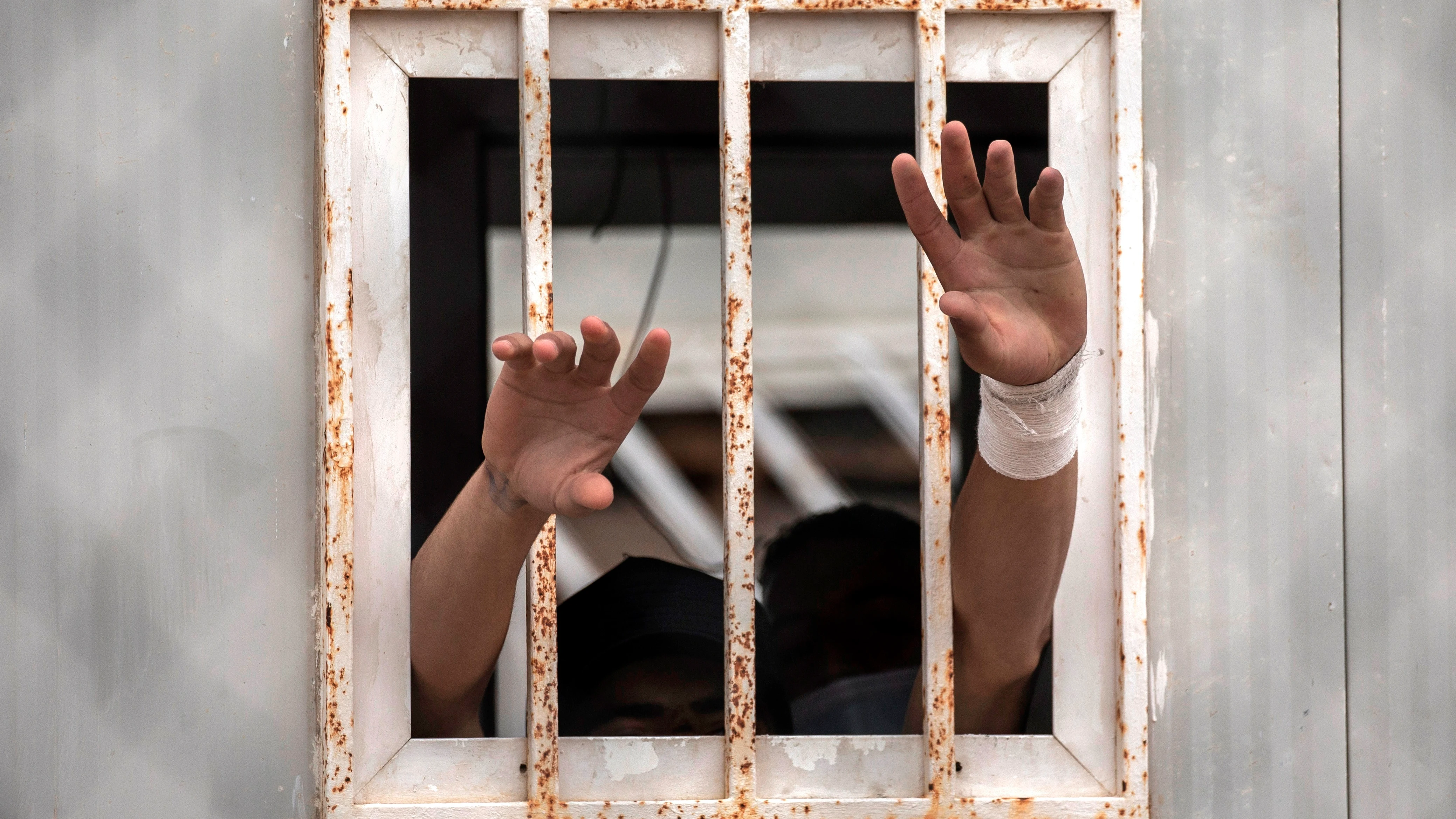 Dos menores sacan sus manos por una ventana del albergue de Piniers