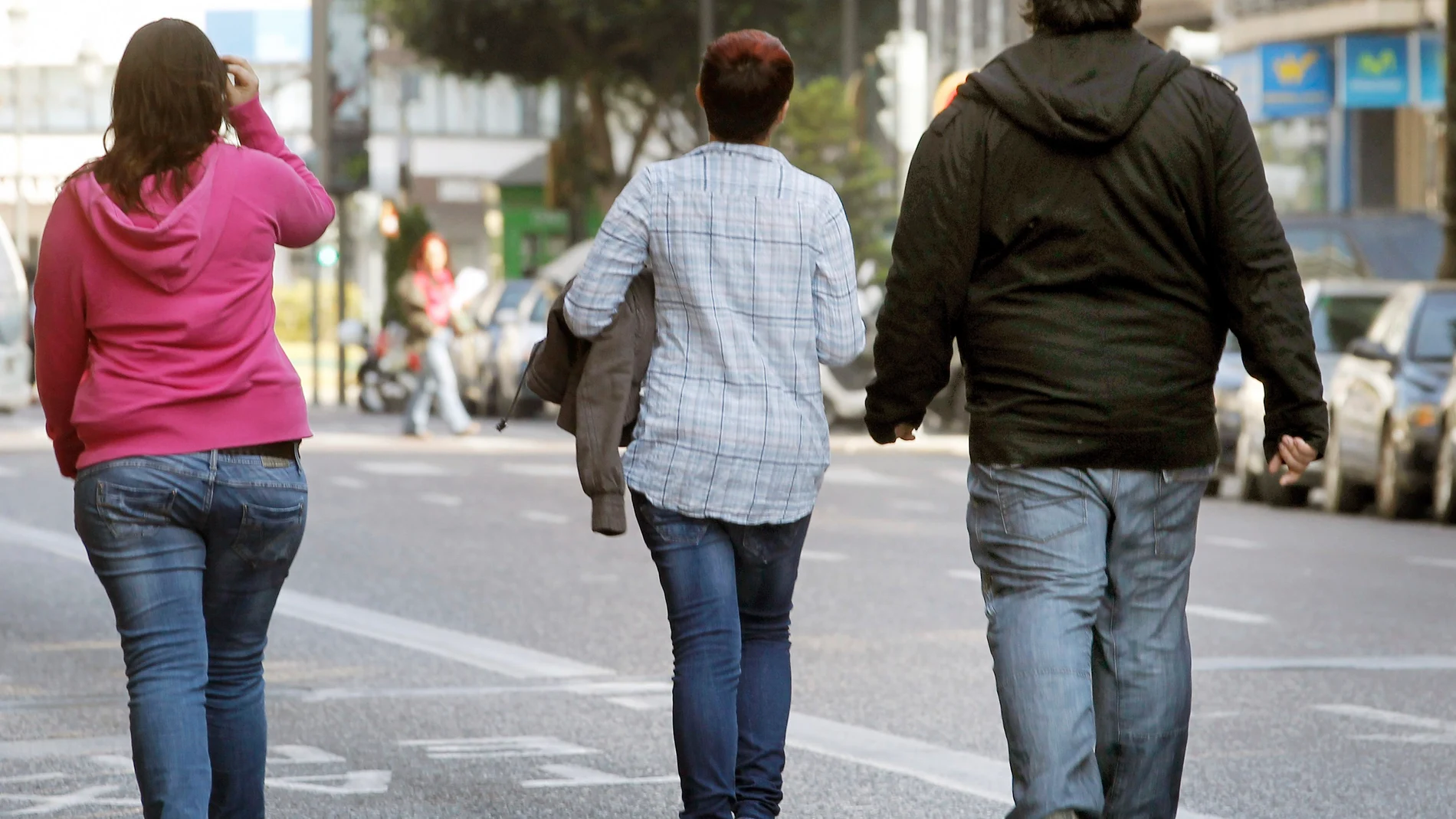 Tres jóvenes pasean por una calle de Valencia