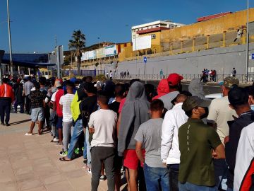 Inmigrantes marroquíes hacen cola desde primeras horas de la mañana de este miércoles, ante la oficina de Asilo y Refugio de la frontera del Tarajal en Ceuta