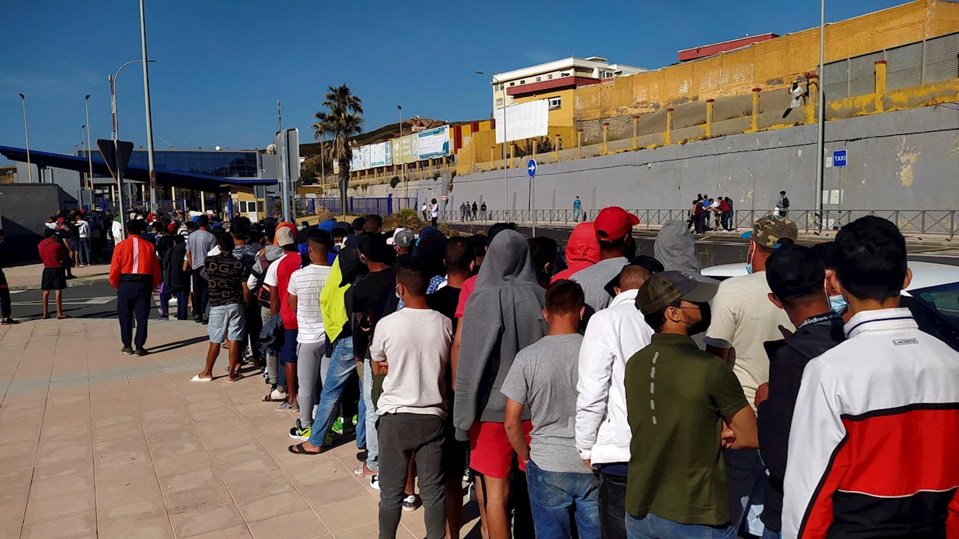 Inmigrantes marroquíes hacen cola desde primeras horas de la mañana de este miércoles, ante la oficina de Asilo y Refugio de la frontera del Tarajal en Ceuta