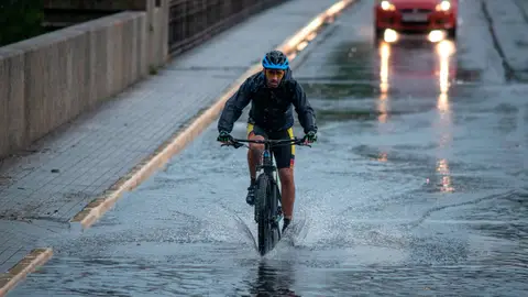 Un ciclista circula por una calle inundada en Ourense Tormentas