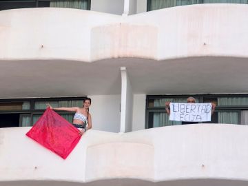 Dos jóvenes que permanecen en aislamiento en el hotel Palma Bellver de Palma saludan desde los balcones de sus habitaciones, este martes en Palma de Mallorca