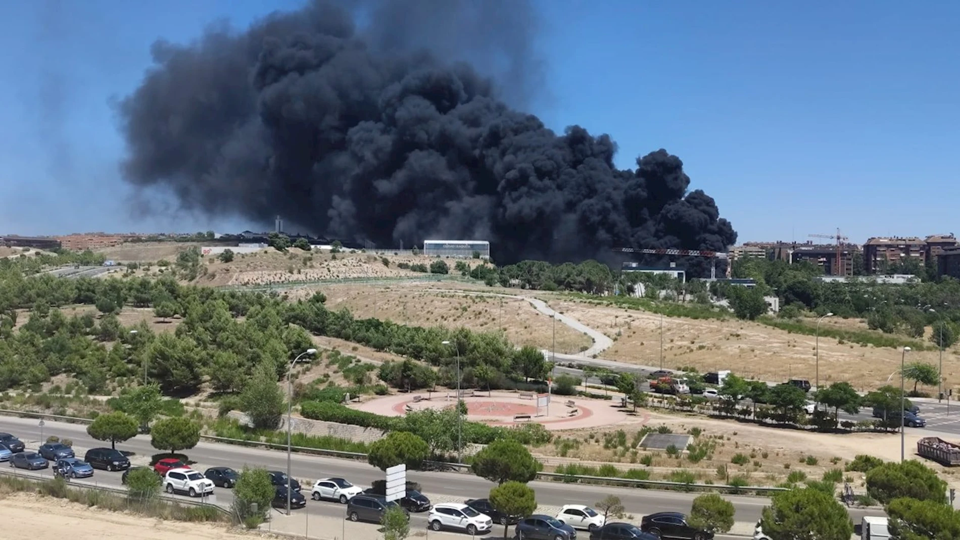Columna de humo del incendio originado este viernes en un edificio de uso comercial en construcción, en la zona de Mirasierra, en el que han ardido plásticos