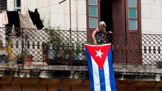 Una mujer sale al balc&oacute;n donde se expone una bandera cubana