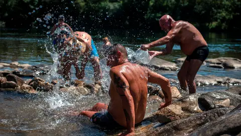 Varios hombres refrescándose por la ola de calor Varios hombres refrescándose por la ola de calor