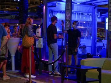 Un empleado toma la temperatura a un joven que hace cola para entrar en un pub en el puerto deportivo de Marbella.