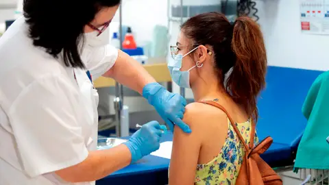 Sanitaria vacunando contra el coronavirus a una joven Sanitaria vacunando contra el coronavirus a una joven