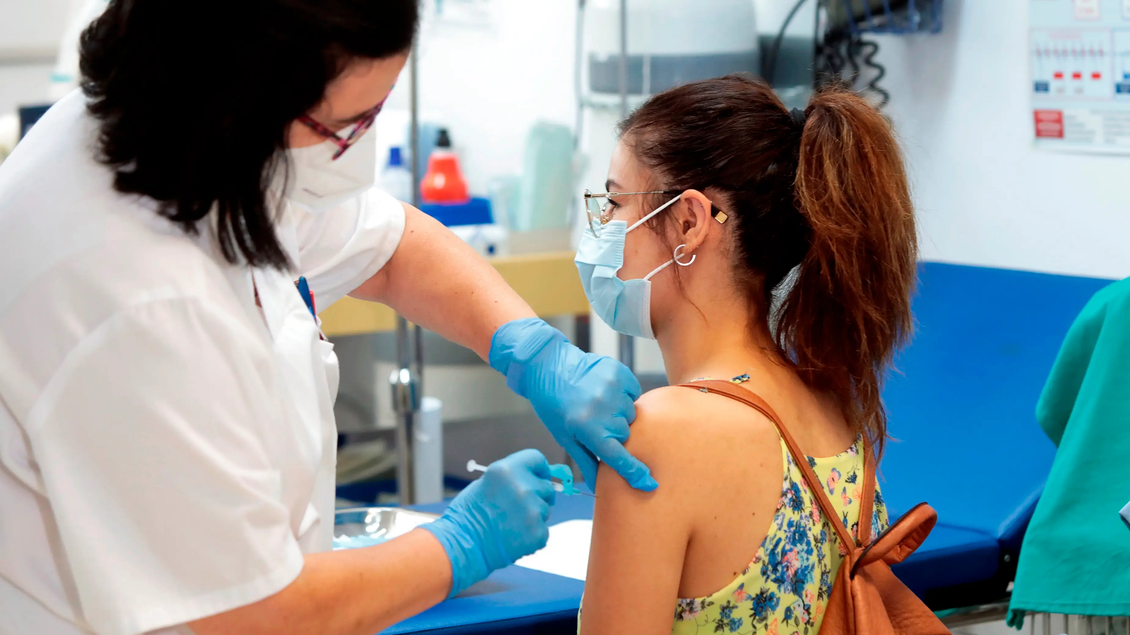 Sanitaria vacunando contra el coronavirus a una joven Sanitaria vacunando contra el coronavirus a una joven