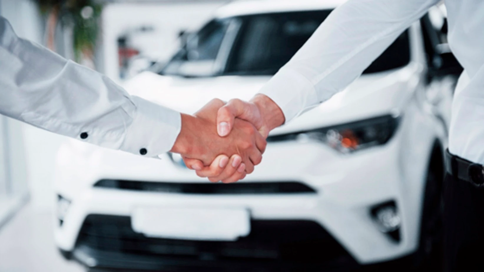 Dos hombres se estrechan las manos ante un coche de renting Dos hombres se estrechan las manos ante un coche de renting